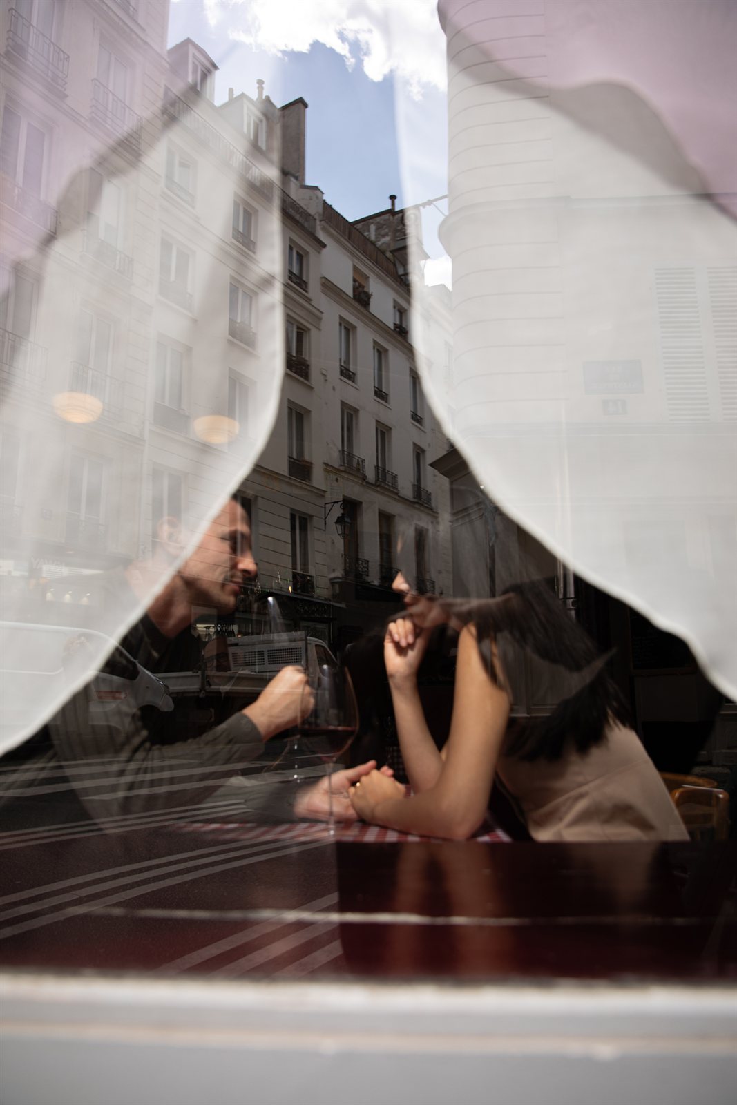 A wine tasting moment seen through the window of a Parisian restaurant.