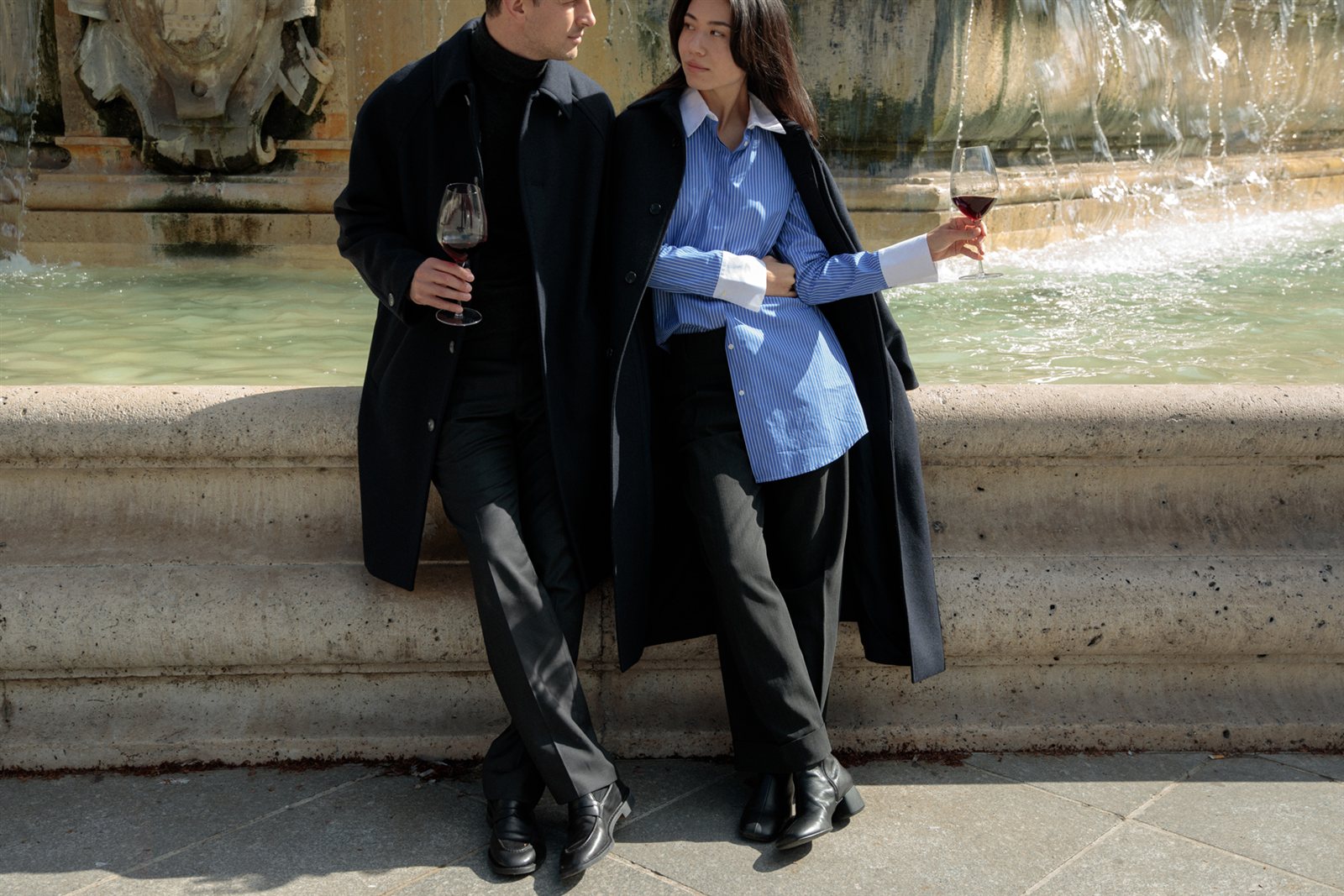 Two people enjoying a glass of wine in front of the Saint-Sulpice Fountain in Paris.