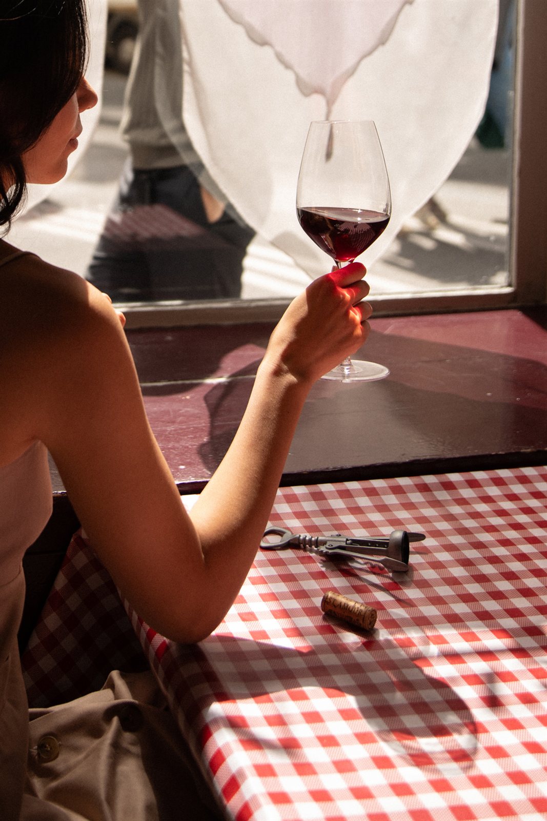 A glass of red wine enjoyed in the daylight of a Parisian bistro.